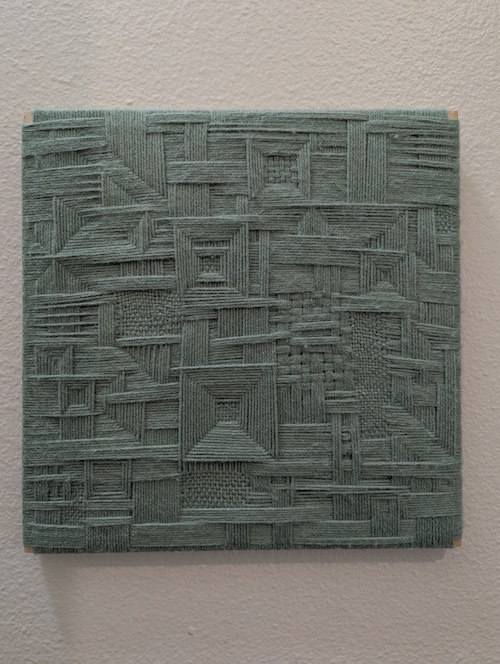A green abstract weaving with repeating square motifs and layered strands