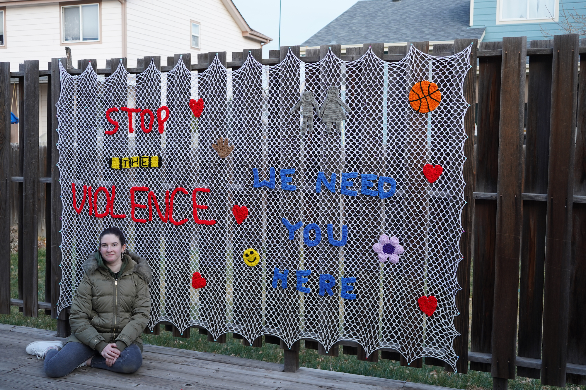 Joey sitting beside her large Stop the Violence yarn-bombing installation