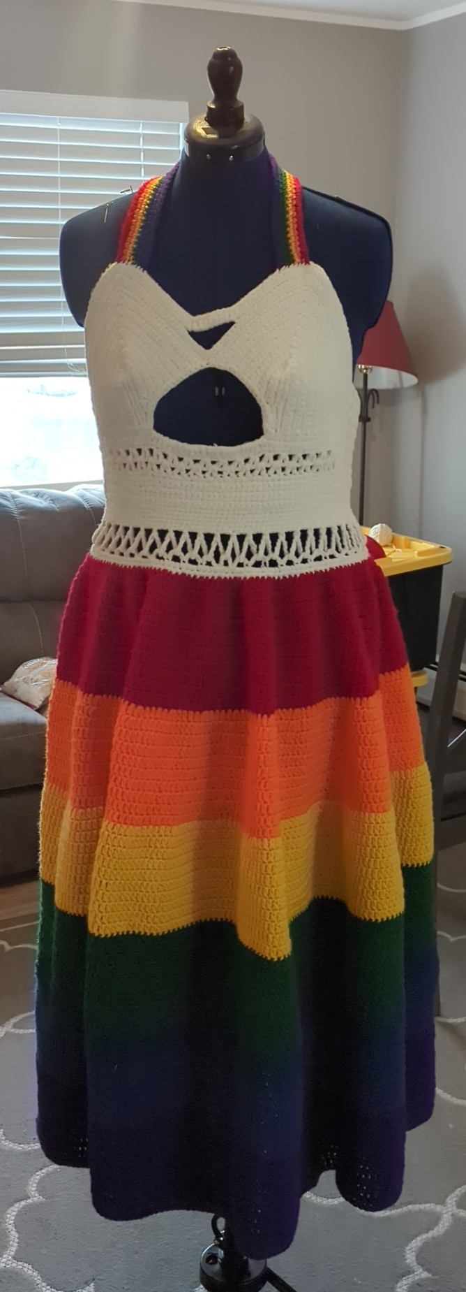 A long crochet dress with a white openwork bodice, rainbow straps, and a rainbow-striped skirt